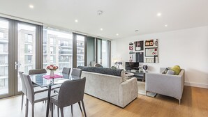 Un apartamento moderno con comedor, sala de estar y un amplio ventanal con vistas a la ciudad.