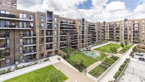 Un moderno complejo de apartamentos con varios balcones, un patio central con vegetación y un área exterior bien cuidada.