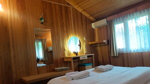 Una habitación con paneles de madera, una cama, un escritorio, un espejo y una ventana.