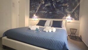 A modern bedroom with a large bed, a ceiling mural, and a small side table. - L'arco e il vico (Naples)