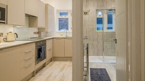 A modern kitchen with a built-in oven, a kettle, and a window.