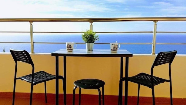 A balcony with a table and two chairs, a potted plant, and a mug. - Dhermi Lighthouse (Dhërmi)