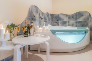 A spa room with a bathtub, candles, and champagne. - Piccadilly Suites and Rooms (Nardò)