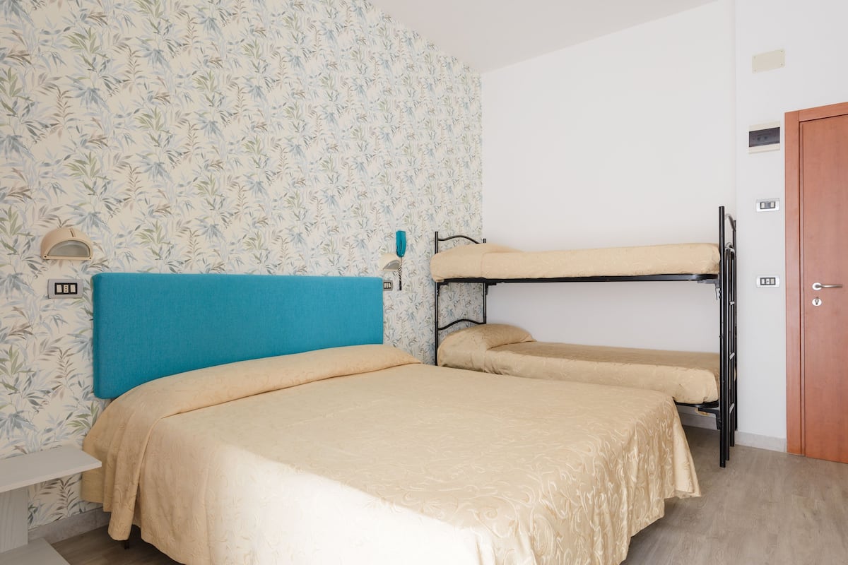 A room with two bunk beds, a blue headboard, and a patterned wallpaper.