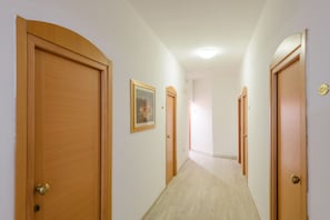 A hallway with wooden doors, a framed picture on the wall, and a light fixture on the ceiling. - Hotel Clipper (Cattolica)