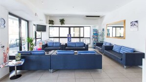 Ein moderner Wartebereich mit Sofas, einem Couchtisch, großen Fenstern und einem Fernseher.