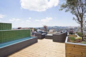 A rooftop terrace with a pool, wicker furniture, and a view of the cityscape. - Hotel Acta The Avenue (Porto)
