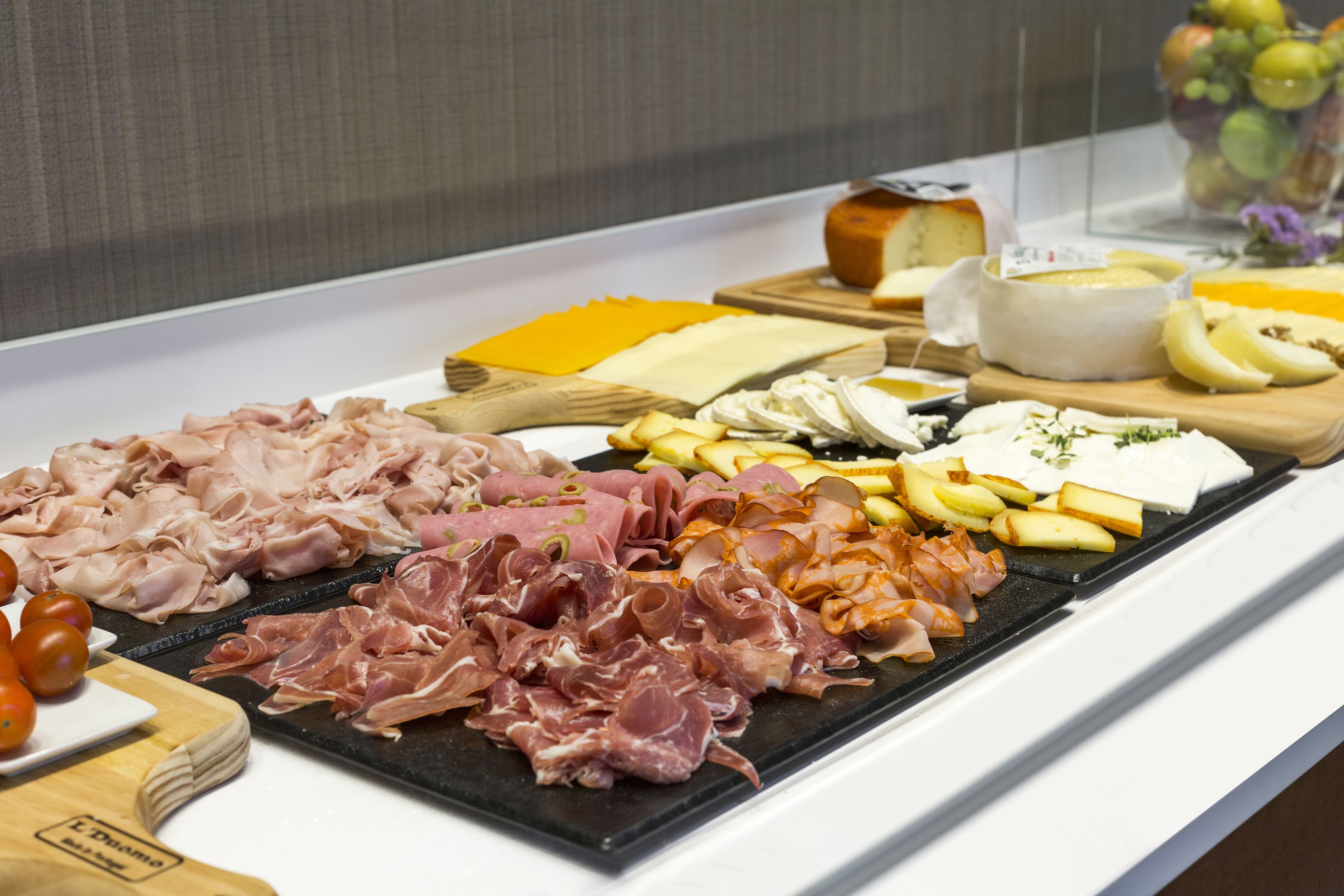 A charcuterie board with various meats, cheeses, and fruits.