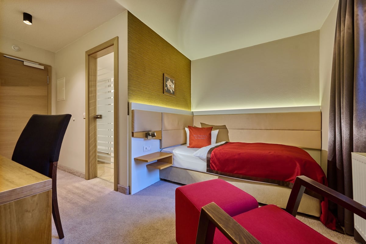 A compact hotel room with a bed, a desk, and a chair.
