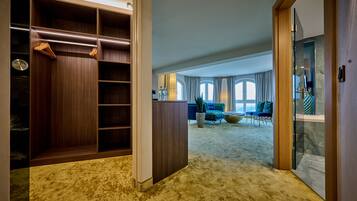 Une pièce spacieuse dotée d’un grand dressing, d’un coin salon avec un canapé et des fauteuils bleus, et offrant une vue sur l’extérieur grâce à de grandes fenêtres.