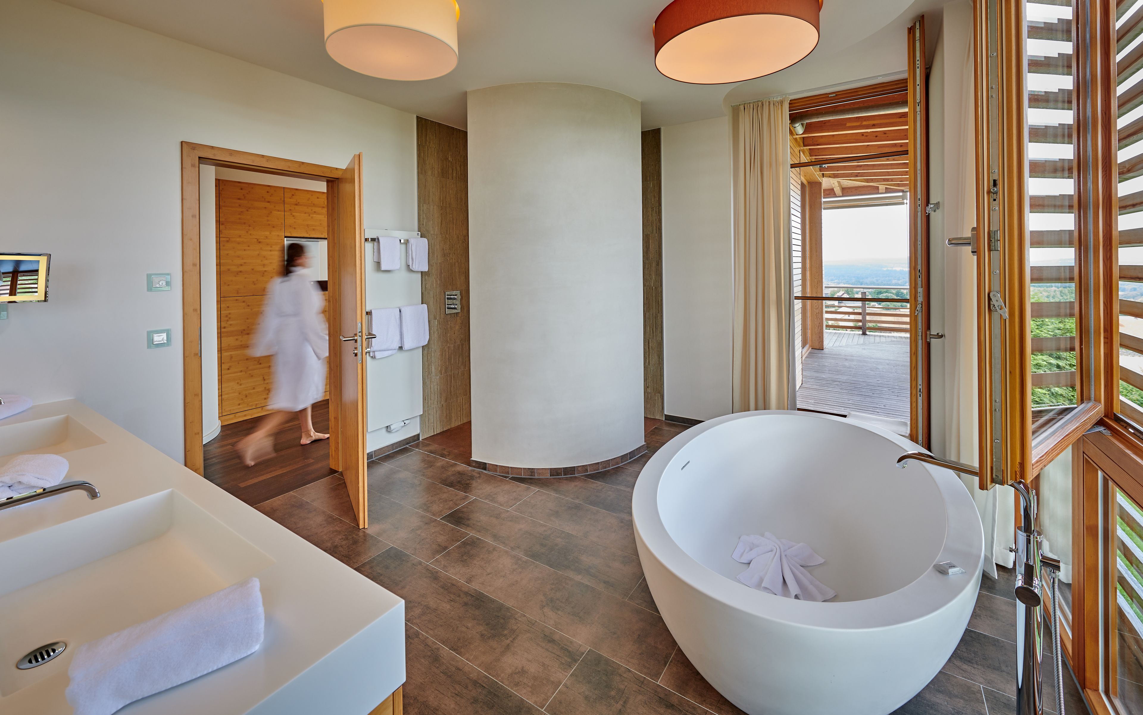 Ein modernes Badezimmer mit einer großen Badewanne, einer bodenebenen Dusche und Holzboden.