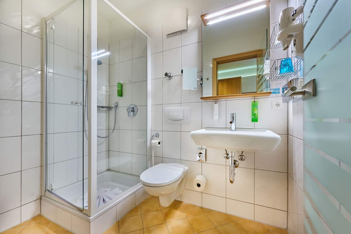A modern bathroom with a glass shower enclosure, a toilet, and a sink.
