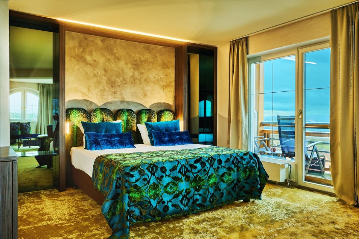 A hotel room with a large bed, a balcony with a view, and a large mirror.