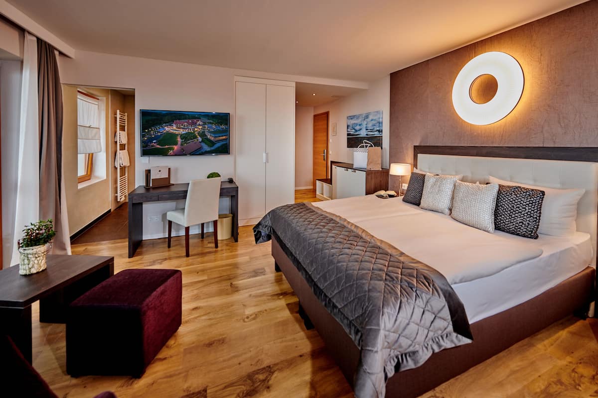 A modern hotel room with a large bed, a desk, and a chair.