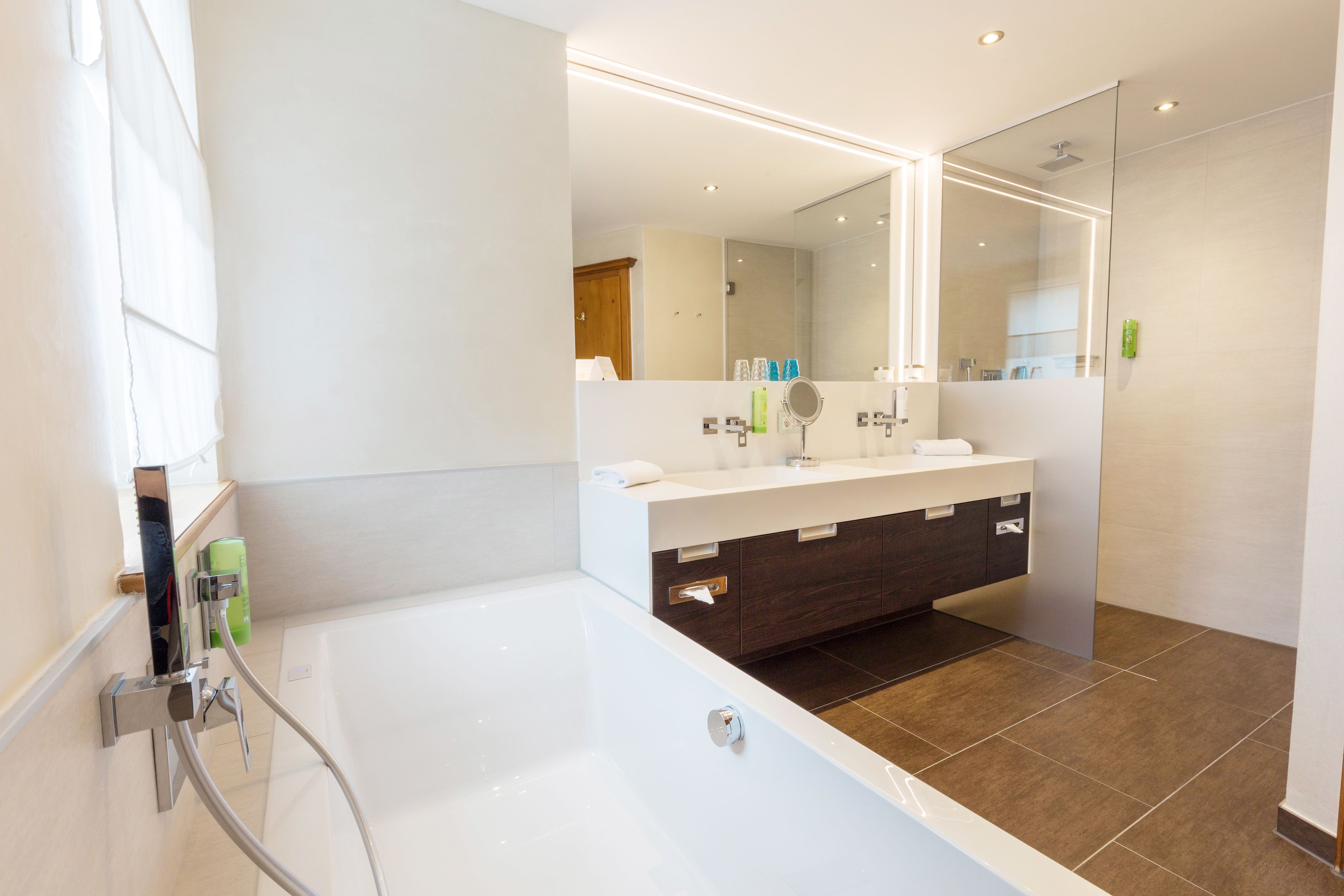 Ein modernes Badezimmer mit einer Badewanne, einem Waschtisch mit Spiegel und einer Duschkabine.
