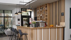 Una zona de bar moderna con mostrador de madera, taburetes y un dispensador de bebidas.