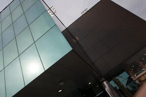 Un edificio moderno con fachada de vidrio y una sección superior de tonos oscuros.
