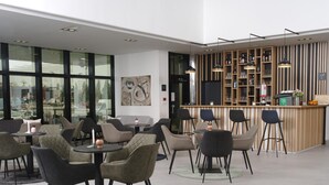 Un bar moderno con mostrador de madera, lámparas colgantes negras y diversas opciones de asientos, como mesas redondas y sillas.