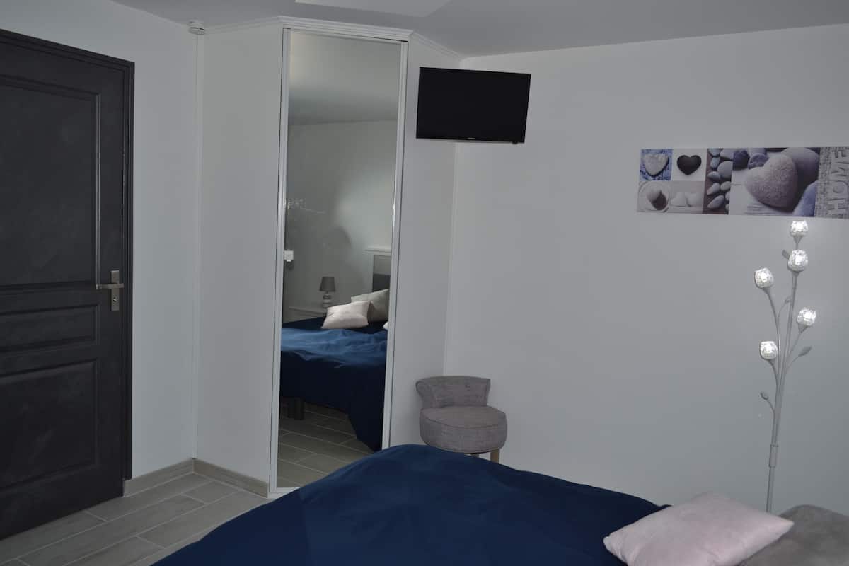 Ein Schlafzimmer mit Bett, Stuhl, Fernseher und einer Wanddekoration.