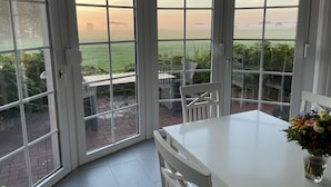 Uma estufa com vista para um campo verde e um pôr do sol.
