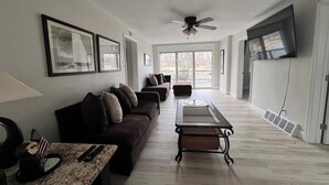A spacious living room with a dark brown sofa, a coffee table, and a ceiling fan.