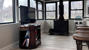 A spacious room with large windows, a fireplace, a television, and a bar area.