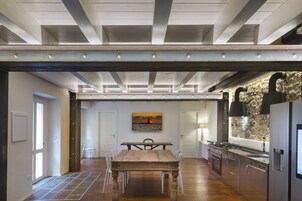 Una cocina amplia con una mesa de madera, sillas blancas y una isla grande con un fregadero y estufa.