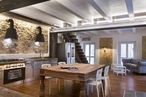 Una cocina amplia con una mesa y sillas de madera, horno empotrado y pared de piedra.