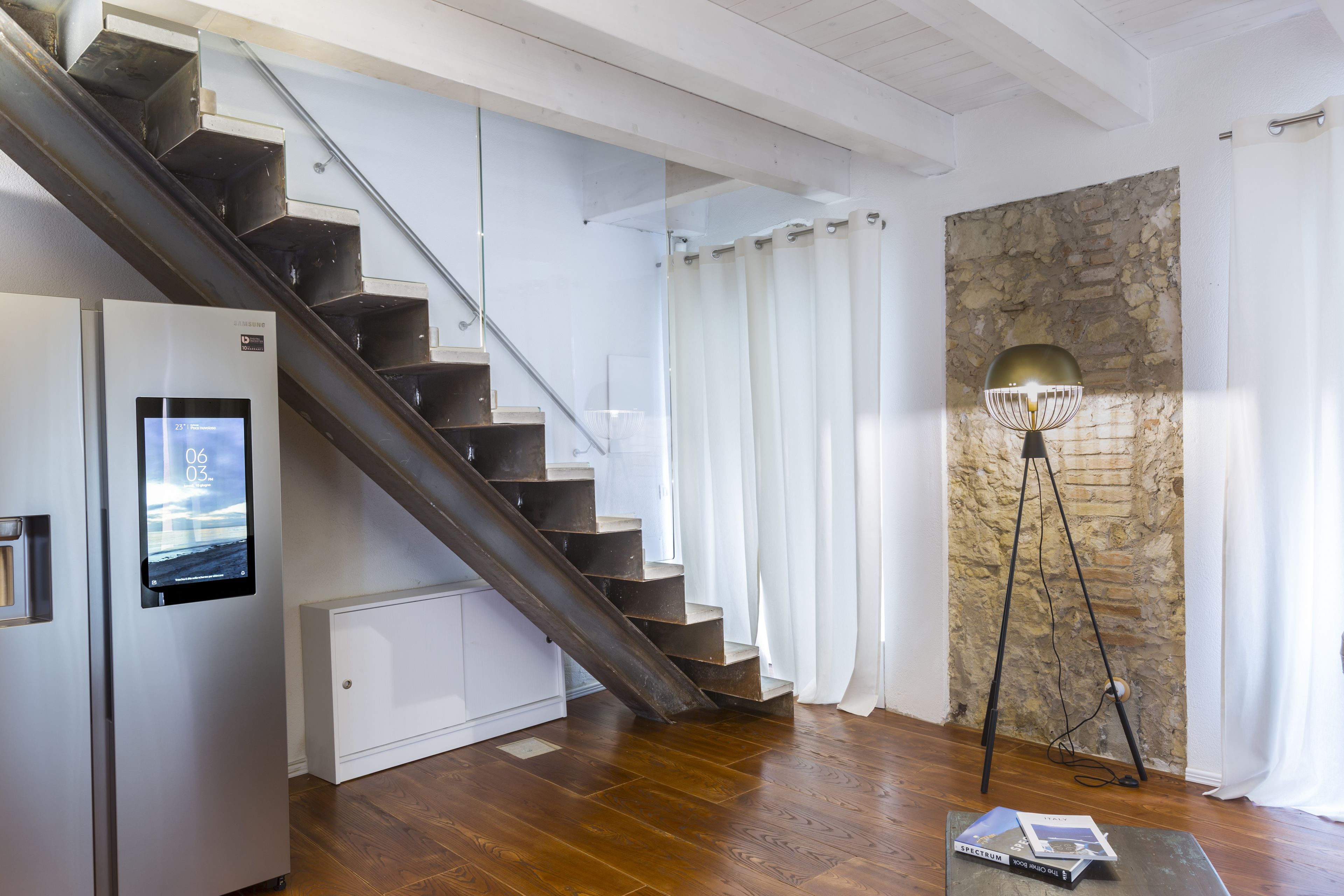 Een modern interieur met een houten trap, een stenen muur en een vloerlamp.