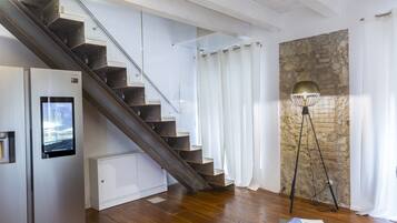 A modern interior with a wooden staircase, a stone wall, and a floor lamp.