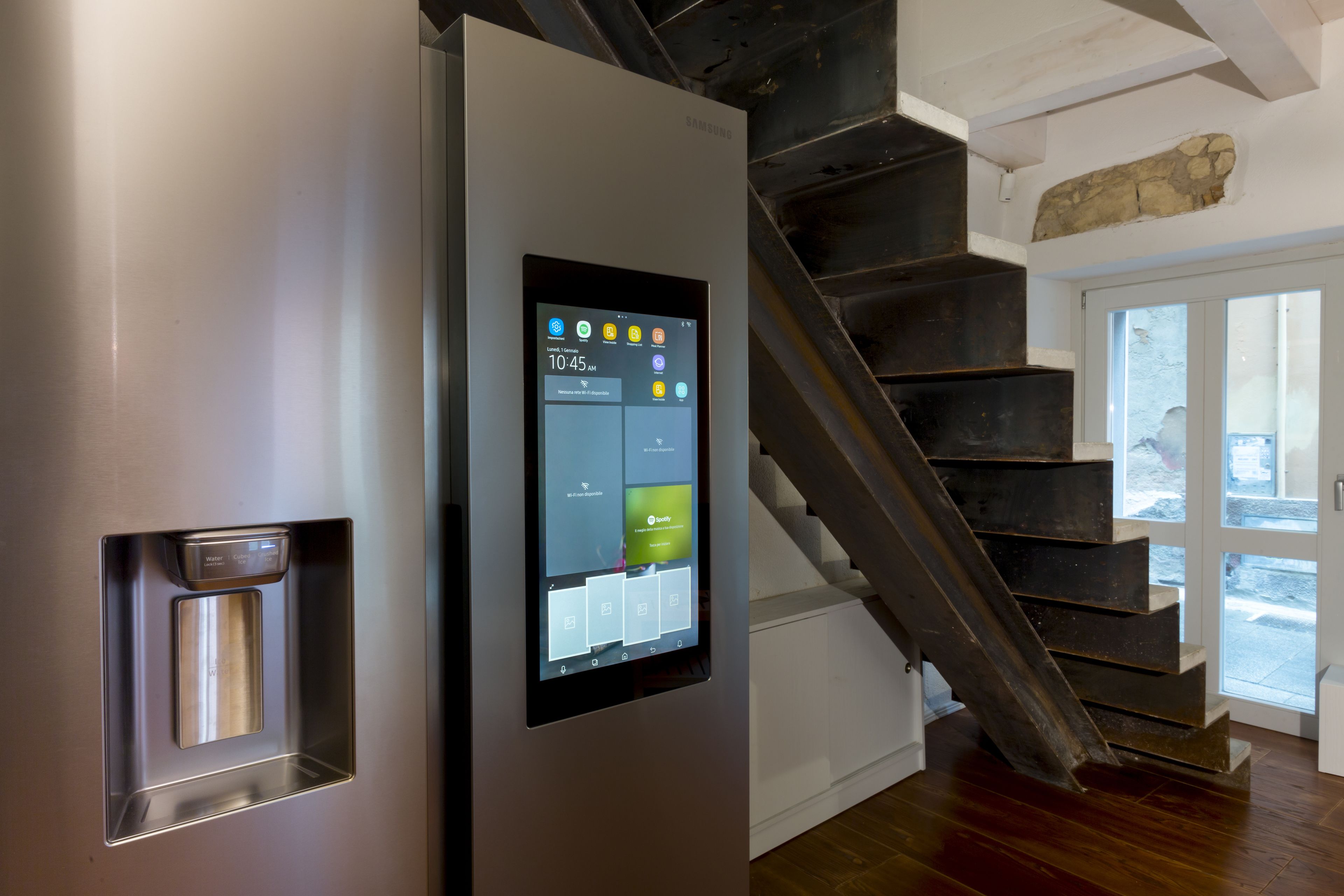A modern interior with a digital display on a door, a staircase, and a stone feature on the wall.