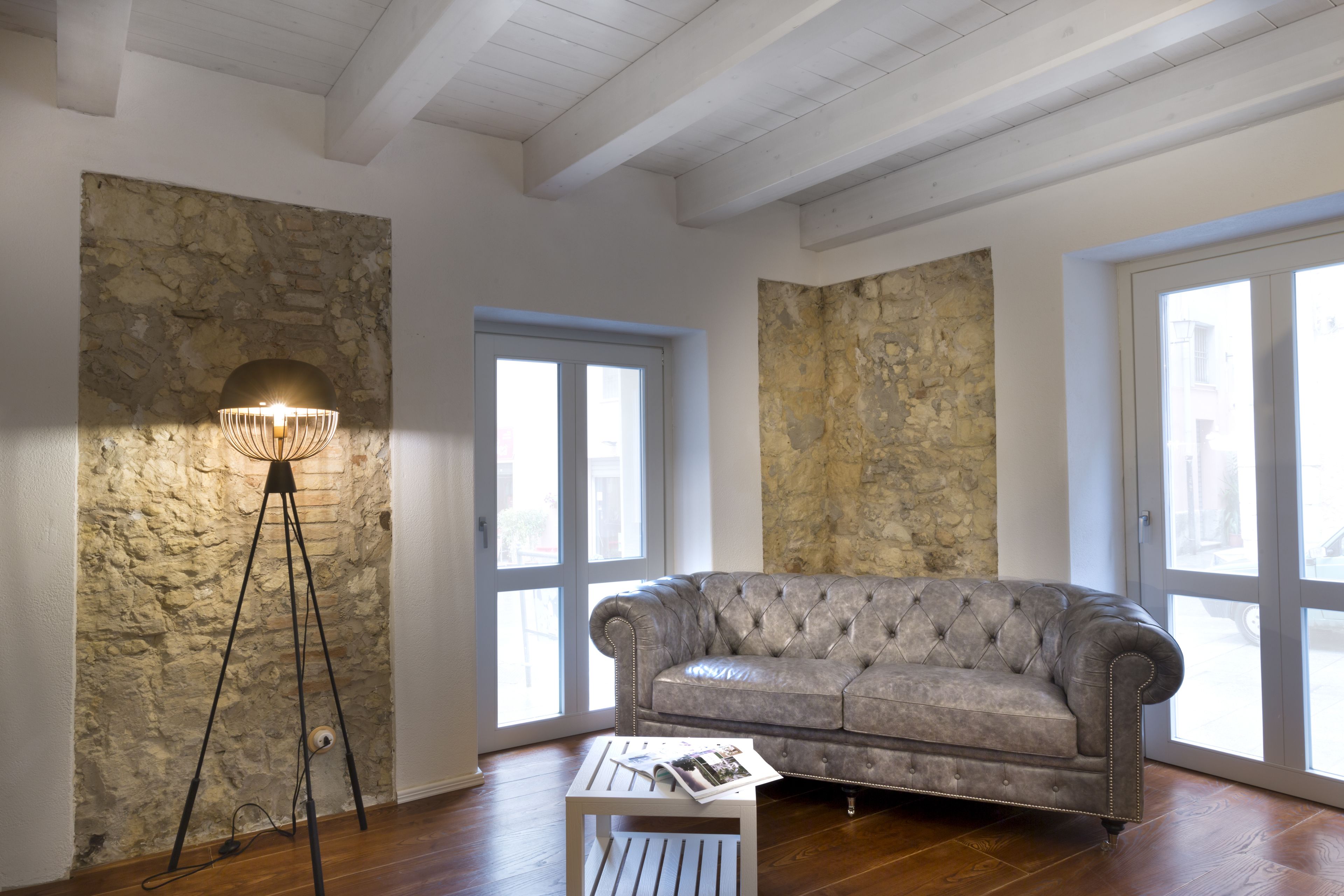 A living room with a tufted leather sofa, a floor lamp, and a small white table.