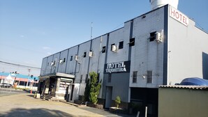A hotel with a tiled facade, multiple air conditioning units, and a sign reading "HOTEL TIQUATIRA".