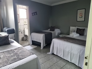 Habitación de hotel con dos camas, un lavamanos y una ventana.