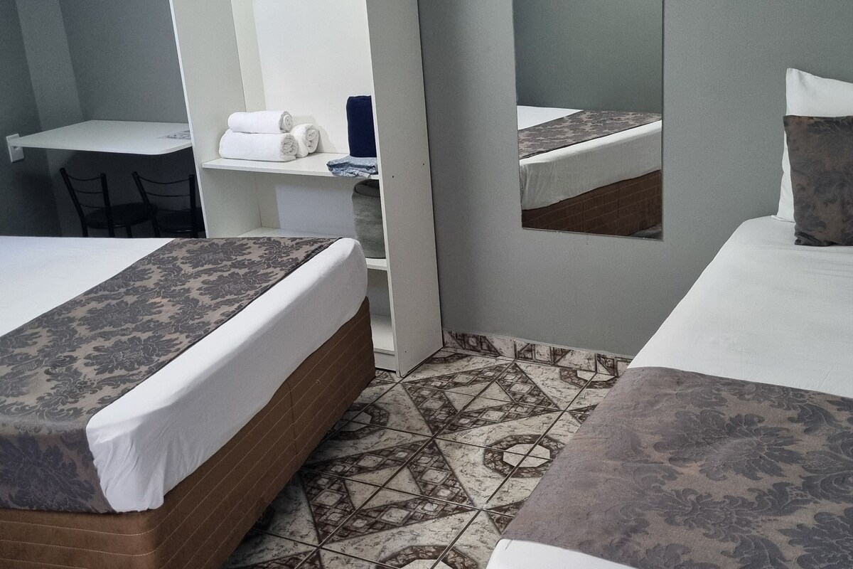 Habitación de hotel con dos camas, un escritorio y una silla.