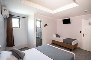 Habitación de hotel con cama, televisión, baño y ventana.