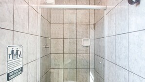 A bathroom with a shower, toilet, and a sign on the wall.