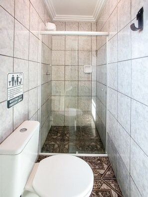 Baño con ducha, inodoro y un cartel en la pared.