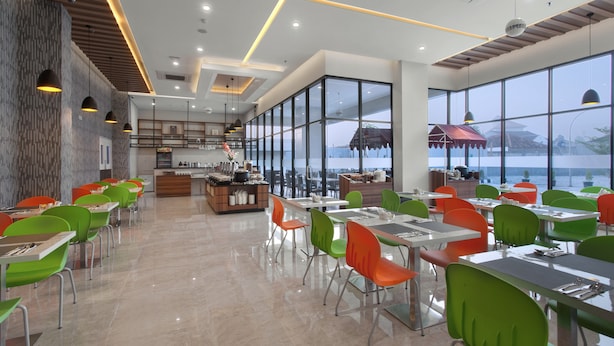 A modern dining area with large windows, a kitchen in the background, and colorful chairs.