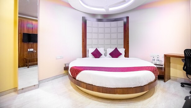 A modern bedroom with a circular bed, a ceiling fan, and a bedside table with a lamp. - Hotel Apex International (Mumbai)