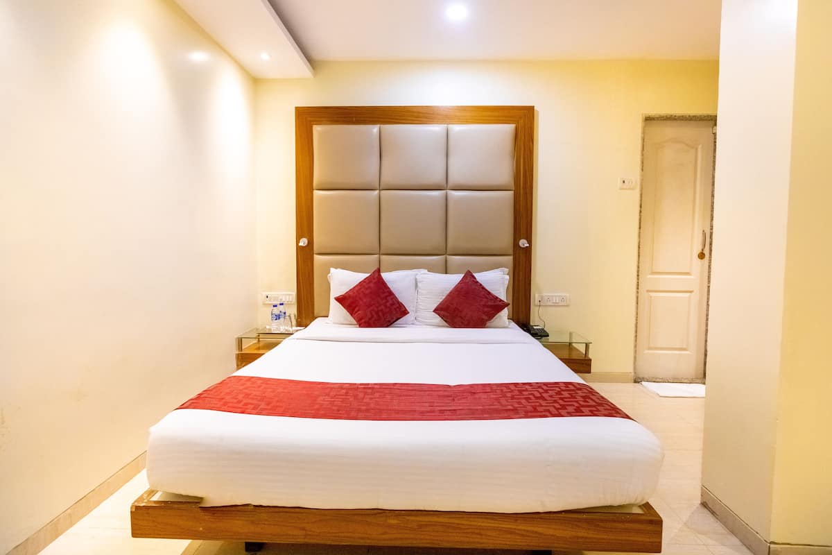 A hotel room with a large bed, a wooden headboard, and a bedside table with a glass top.
