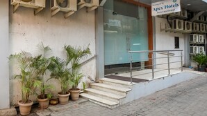 A hotel entrance with multiple air conditioning units, a sign for Apex Hotels International, and potted plants. - Hotel Apex International (Mumbai)
