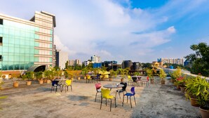 A rooftop terrace with outdoor seating and potted plants, overlooking a cityscape. - Hotel Apex International (Mumbai)