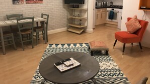 Un espace de vie compact comprenant un coin repas, un canapé, un téléviseur et une kitchenette.