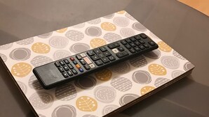 Une télécommande posée sur une table à motifs.