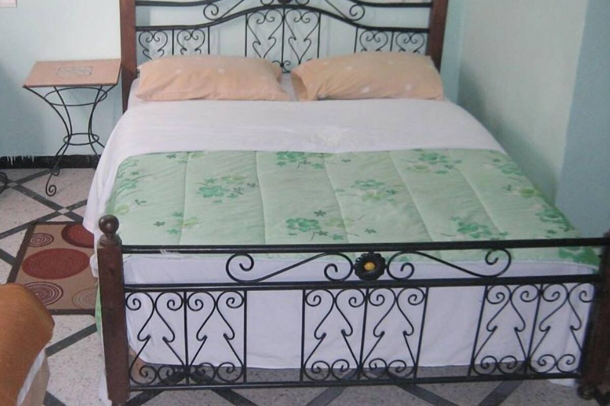 Uma cama com estrutura metálica e colcha florida.