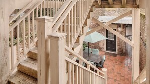 Un escalier en bois mène à un espace patio aménagé avec une table et des chaises.
