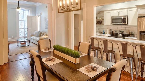 Un coin repas avec une table en bois, des chaises, un élément décoratif au centre, et une cuisine en arrière-plan.