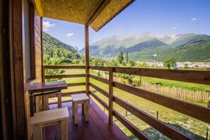 A wooden deck with a view of mountains and a grassy field. - guesthouse gio (Mestia)