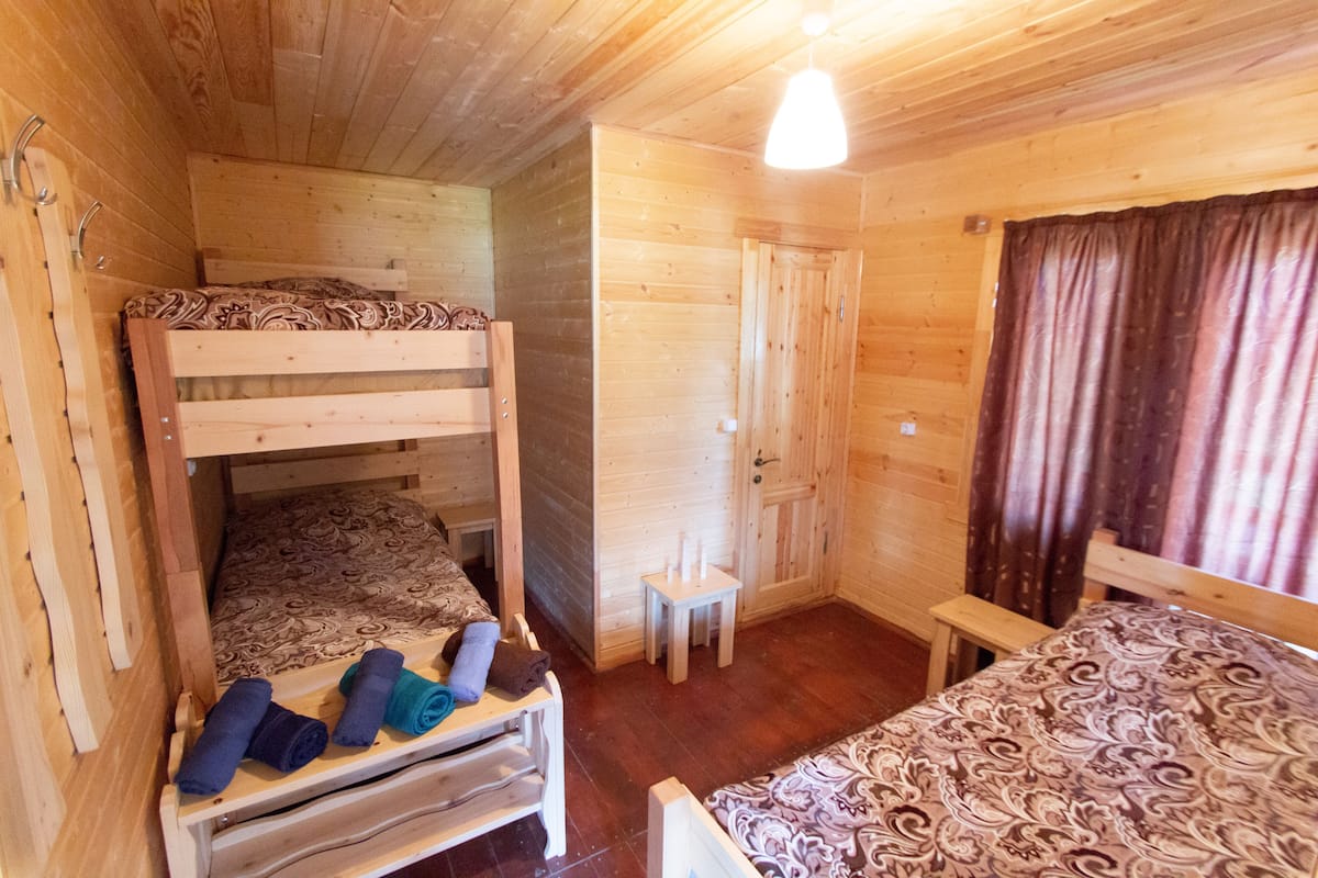 A wooden cabin room with bunk beds, a small table, and a door.